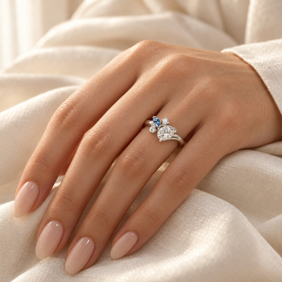 DR0332 diamantring med pæreformet diamant og blå markise i hvidguld, båret på hånd