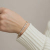 Pear and round lab grown diamond bracelet in 14k gold worn on hand