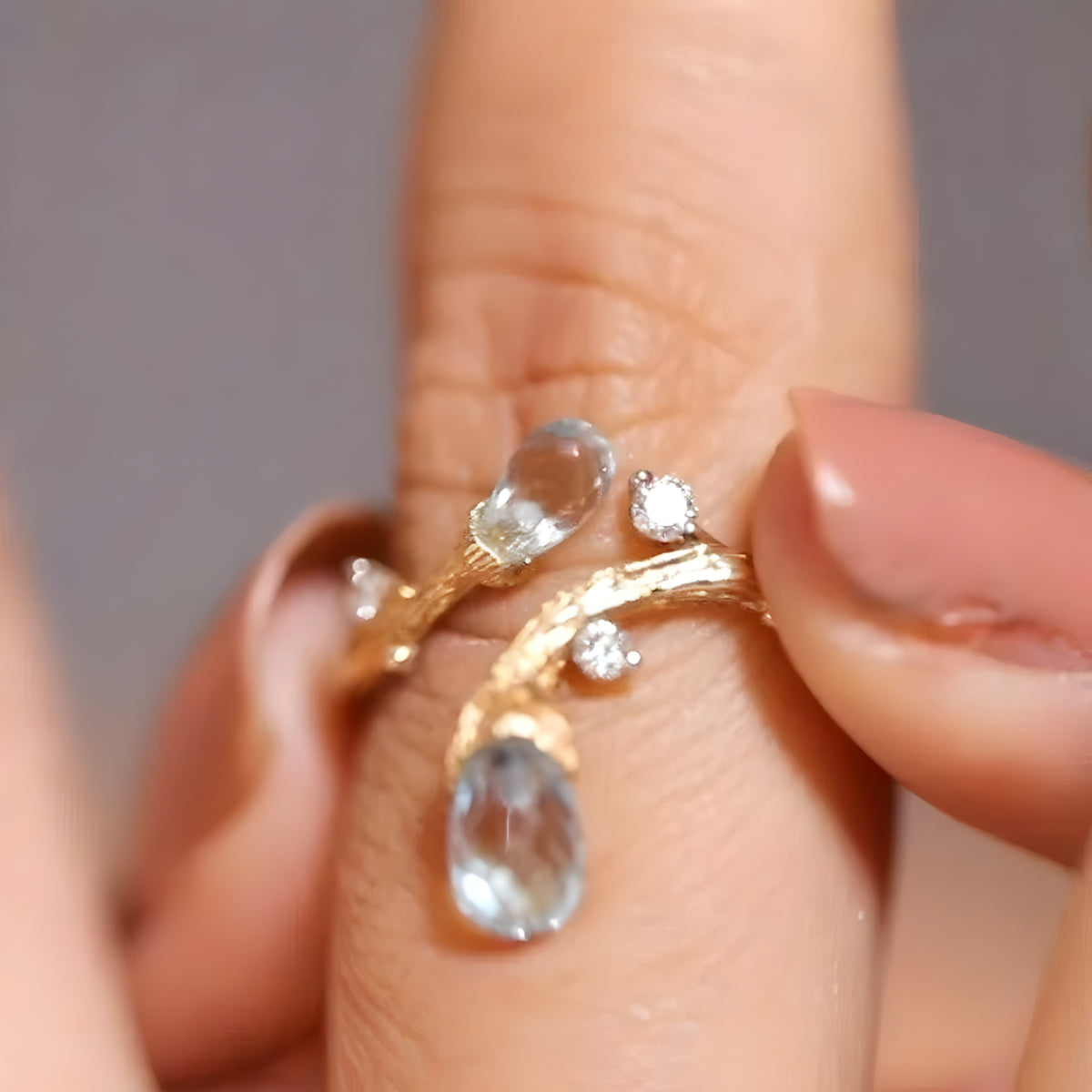 Topas- og diamantring i 14 karat gulguld holdt mellem to fingre